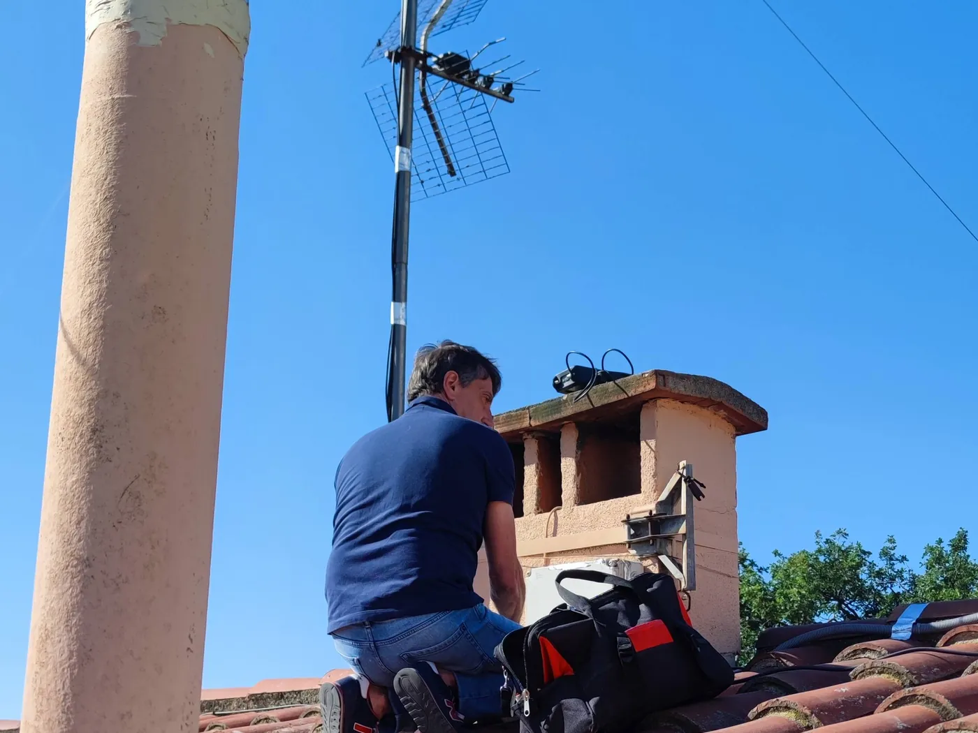 Technicien ASD Electronique installant une antenne râteau sur un toit à Perpignan